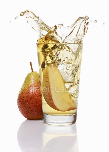 Wedge of pear falling into glass — Stock Photo