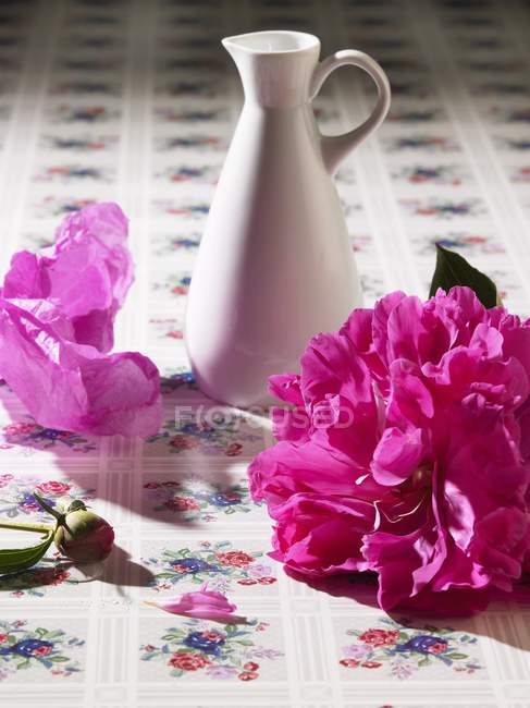 Nahaufnahme einer Pfingstrose mit Vase auf blumig gemusterter Oberfläche — Stockfoto