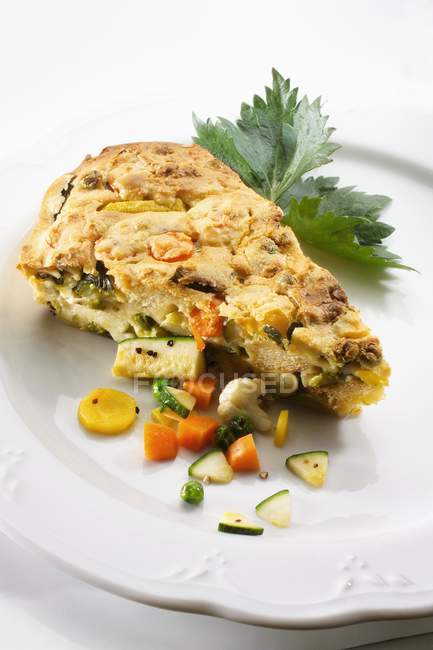 A piece of vegetable tart  on white plate over white background — Stock Photo