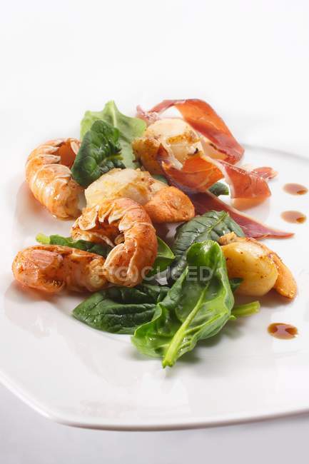 Fried seafood with spinach and bacon  on white plate — Stock Photo