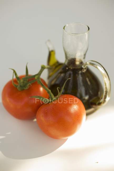 Fresh tomatoes and carafe of oil — Stock Photo