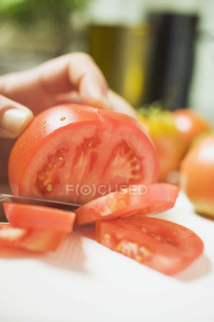 Человеческая рука Нарезание помидоров — стоковое фото