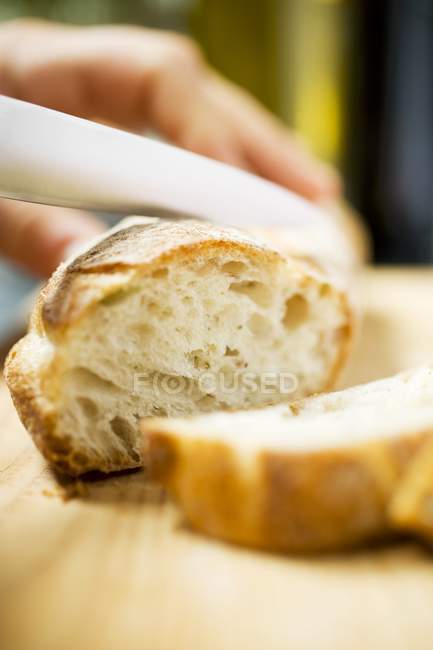 Hand Slicing baguette — Stock Photo