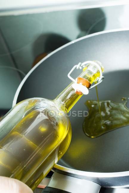 Verter el aceite de oliva en la sartén - foto de stock