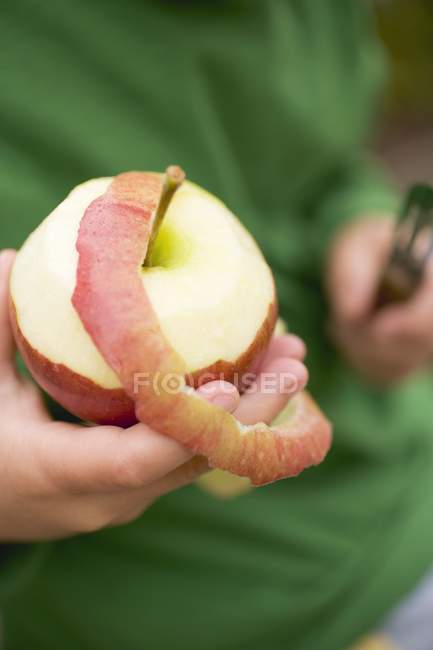 Enfant épluchage pomme rouge — Photo de stock