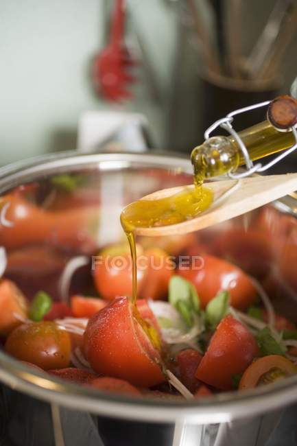 Наливаємо оливкову олію на томатний салат — стокове фото