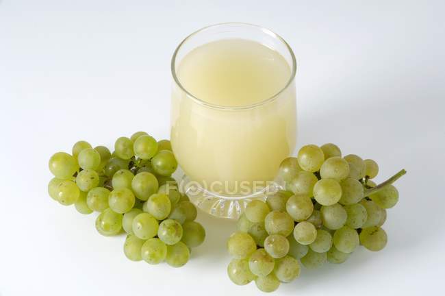 Vaso de jugo y racimos de uvas - foto de stock
