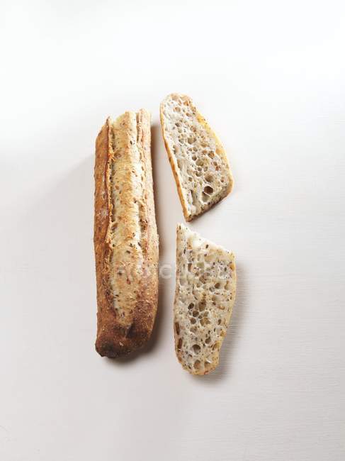 Partly sliced grain baguette — Stock Photo