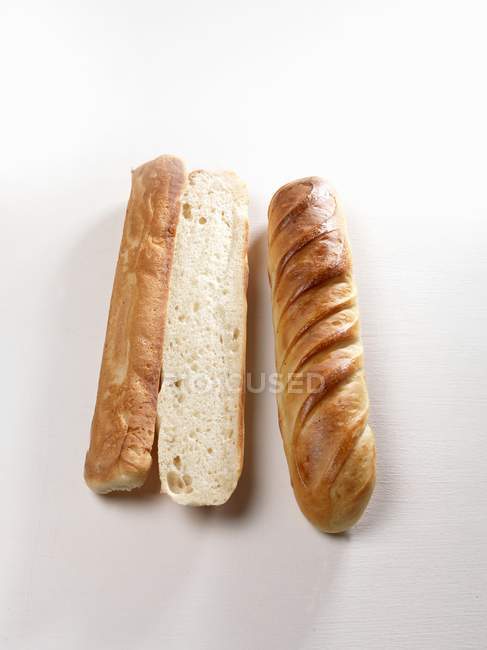 Closeup view of whole and cut Brioches on white surface — Stock Photo