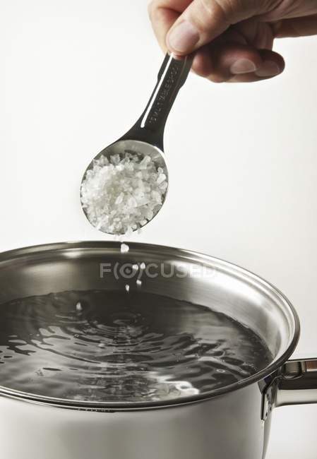 Salt being sprinkled into pot — Stock Photo