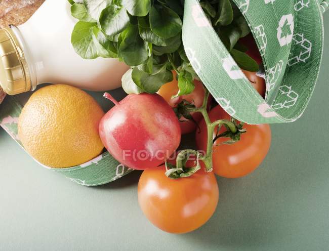 Bolsa de compras de lona con tomates, fruta y una botella de leche - foto de stock
