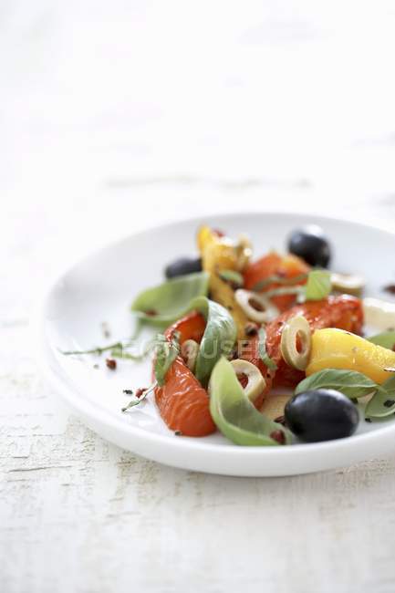 Салат из перца с оливками и базиликом на белой тарелке — стоковое фото