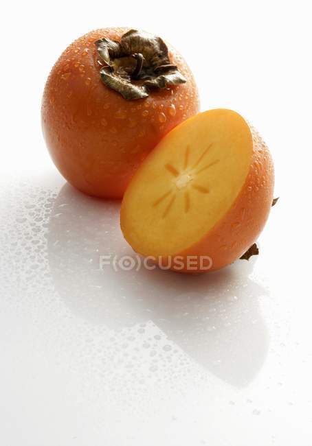 Whole and halved Sharon fruits — Stock Photo