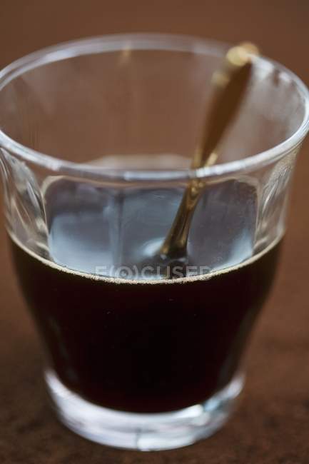 Vista de primer plano de café y ron con cuchara en vidrio - foto de stock