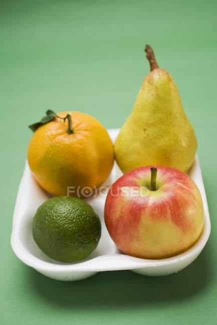 Lima y manzana en bandeja de poliestireno - foto de stock