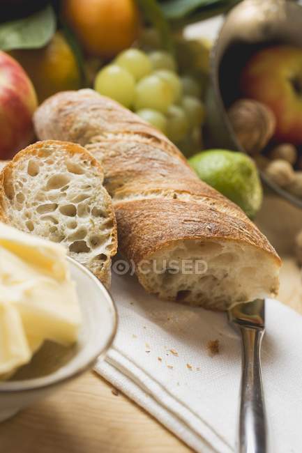 Partly sliced baguette with fruits — Stock Photo