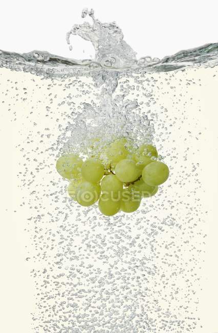 Grapes falling into champagne — Stock Photo