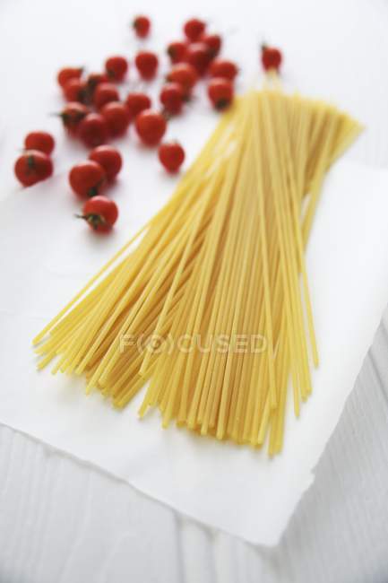 Raw spaghetti pasta and cherry tomatoes — Stock Photo