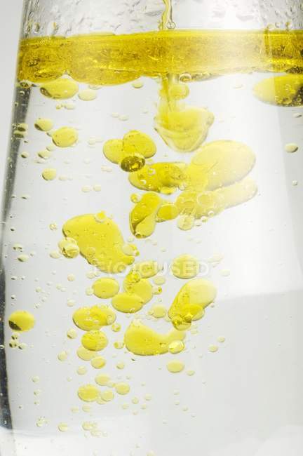 Gotas de aceite en un vaso de agua - foto de stock