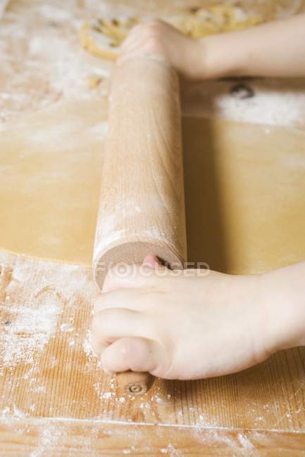 Cropped view of child hands rolling out pastry — Stock Photo