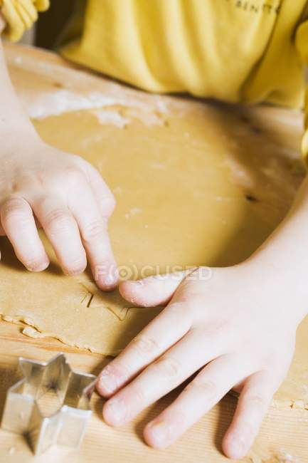 Closeup view of child cutting out biscuits — Stock Photo