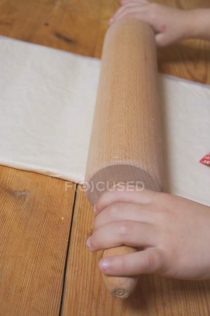 Крупный план детских рук, выкатывающих слоеное тесто — стоковое фото