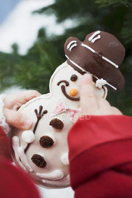 Child holding snowman biscuit — Stock Photo