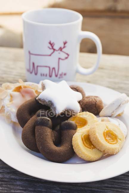 Plate of biscuits in front of Christmas cup — Stock Photo