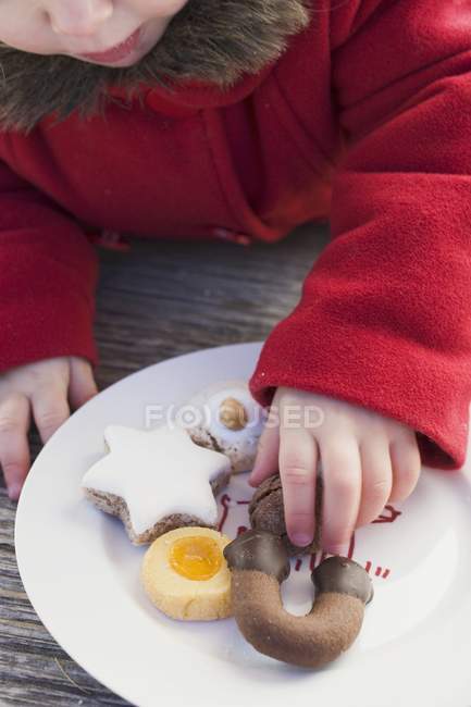 Recortado vista de chica tomando Navidad galleta de plato - foto de stock