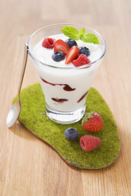 Крупный план йогурта с различными ягодами в стакане — стоковое фото