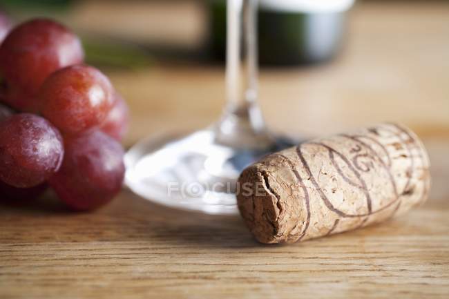 Vista close-up de uvas e cortiça perto de copo de vinho — Fotografia de Stock