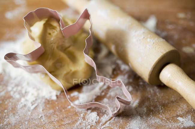 Dough, biscuit cutter and rolling pin — Stock Photo