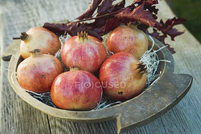 Pomegranates with autumn leaves — Stock Photo