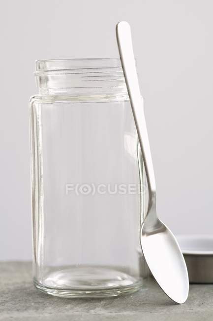 Vista close-up de uma colher encostada a um frasco de rosca — Fotografia de Stock