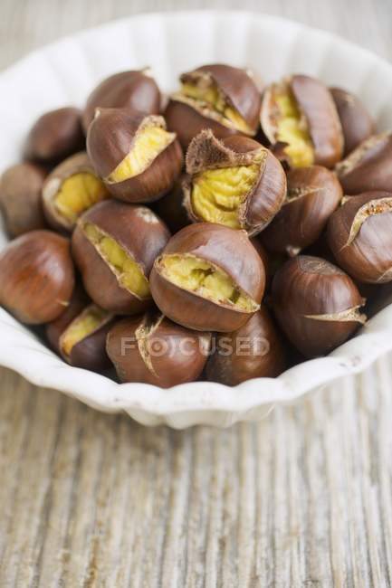 Roasted chestnuts in white bowl — Stock Photo
