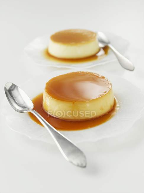 Closeup view of Creme caramel with spoons on plates — Stock Photo