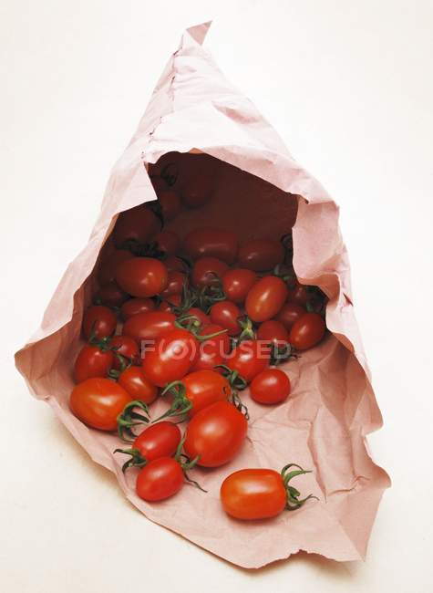 Un montón de tomates en bolsa de papel - foto de stock