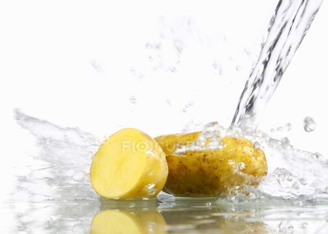 Patatas crudas en agua - foto de stock