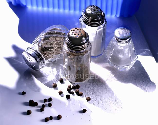 Closeup view of salt and pepper shakers and pepper corns — Stock Photo