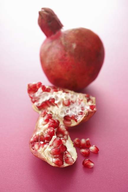 Whole pomegranate and pieces of pomegranate — Stock Photo