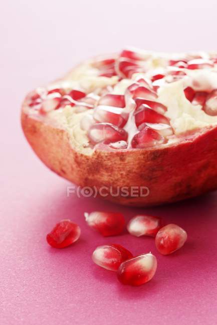 Half pomegranate and pomegrante seeds — Stock Photo