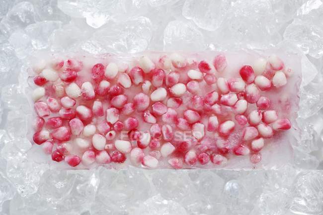 Vista close-up de sementes de romã congeladas em um bloco de gelo — Fotografia de Stock