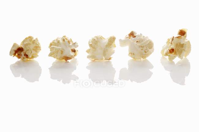 Ряд попкорну на білому — стокове фото