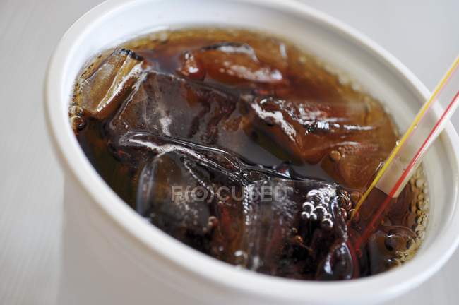 Closeup view of Cola in plastic cup with ice and straw — Stock Photo
