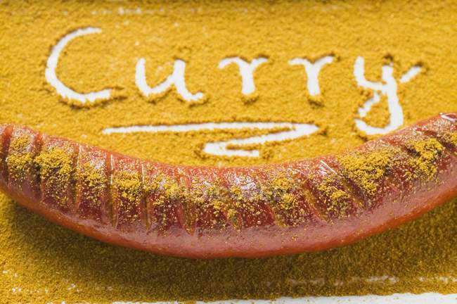Vista close-up de Currywurst ea palavra Curry escrito em pó de curry — Fotografia de Stock