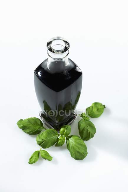 Vista elevada de uma garrafa de vinagre balsâmico e manjericão fresco — Fotografia de Stock