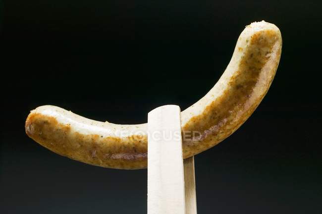 Sausage in wooden tongs — Stock Photo