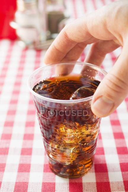 Vista de cerca de la mano sosteniendo la taza de plástico de Cola - foto de stock