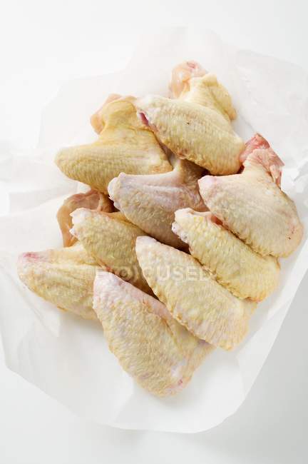 Alas de pollo frescas sobre papel - foto de stock