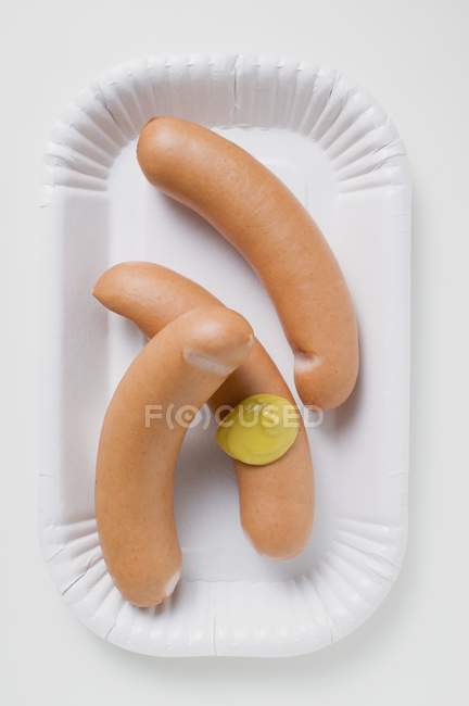 Frankfurters con mostaza sobre plato de papel - foto de stock
